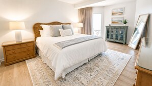 Un dormitorio con cama, mesitas de noche, cómoda, armario y ventana con cortinas.