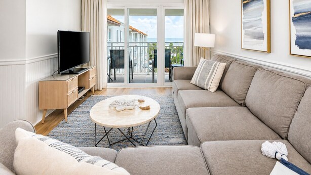 Una sala de estar moderna con sofá, televisión y un balcón con vistas.