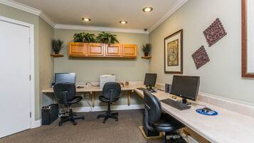 A home office with two desks, two chairs, a printer, and decorative plants.