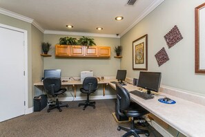 A home office with two desks, two chairs, a printer, and decorative plants.