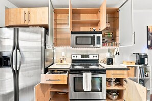 A compact kitchen with a stainless steel refrigerator, a microwave, an oven, and a stove.