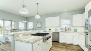 A modern kitchen with white cabinets, a central island with a stove, and a dishwasher.