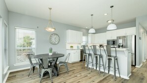 A modern kitchen with white cabinets, stainless steel appliances, and a central island with bar stools.