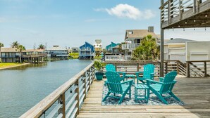 A waterfront property with a wooden deck, turquoise Adirondack chairs, and a view of the water.