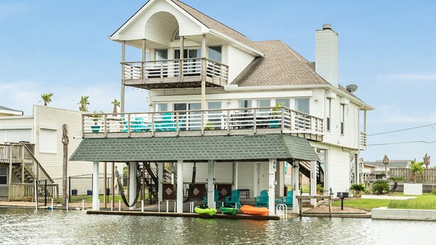 A two-story house with a balcony and a covered dock area.