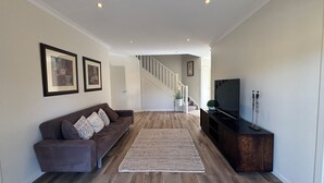 Un salon moderne avec un canapé, un téléviseur et un escalier menant à un autre niveau.