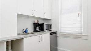 A kitchen with white cabinets, a coffee maker, a microwave, and a dishwasher. - Modern Beachfront Suite 304 (Ocean City)
