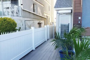 A residential building with a white picket fence, a garage door marked with the number 405, and potted plants on the porch. - Modern Beachfront Suite 304 (Ocean City)