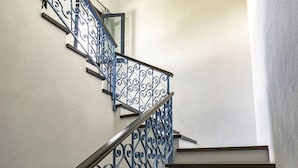 Eine Treppe mit aufwendiger Metallgeländer und einer schlichten Wand.