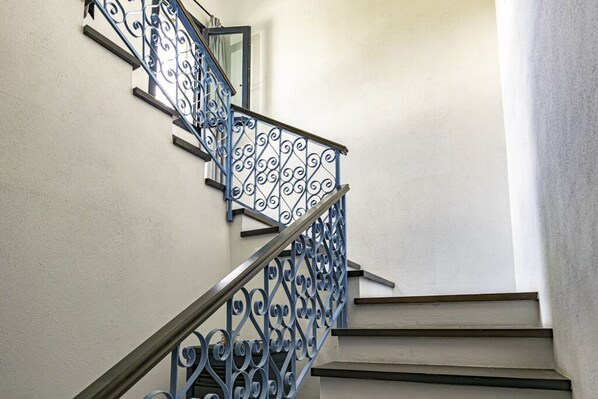 Una escalera con barandales metálicos ornamentados y una pared lisa.