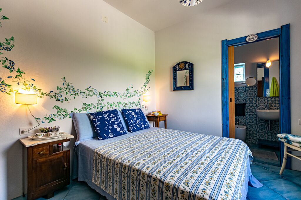A bedroom with a bed, bedside table, and a mirror.