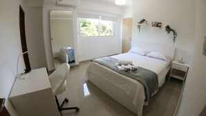 Een schone, moderne slaapkamer met een bed, nachtkastje, stoel en bureau.
