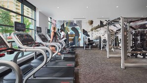 A gym with treadmills, weight machines, and a large mural on the wall. - Global Luxury Suites Clarendon Metro (Arlington)