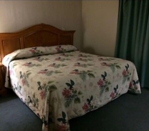 Cozy retreat with a single bed, floral-patterned bedspread, and a nightstand with a lamp.