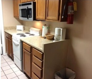 Efficient kitchen with microwave, stove, coffee maker, and refrigerator.