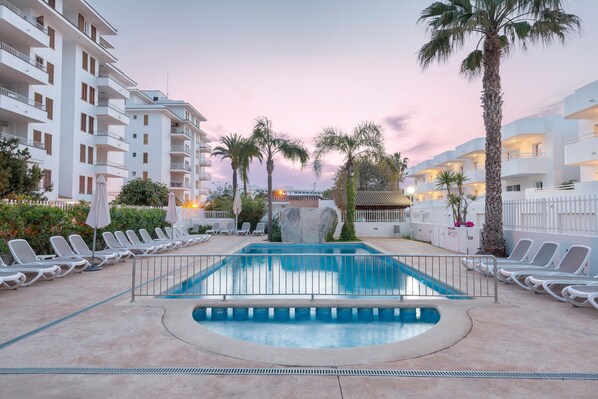 Una piscina al aire libre, sillones reclinables de piscina