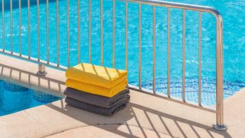 Una piscina al aire libre, sillones reclinables de piscina