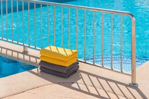 Zona de piscina con barandilla metálica y una pila de toallas.