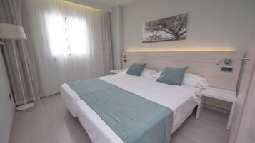 Habitación de hotel moderna con una cama grande, una mesita de noche, una lámpara y un cuadro en la pared.