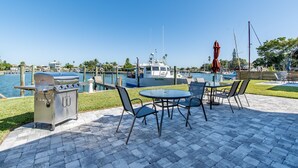 An outdoor patio with a grill, seating, and a view of a marina.