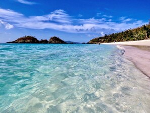 A beach with clear turquoise water, a sandy shore, and a small island in the distance. - EPIC views from every room! Large 2-Bed, 2-Bath with AC and Solar! (Coral Bay)