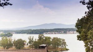 Una vista di un lago con montagne sullo sfondo, circondato da alberi e edifici.