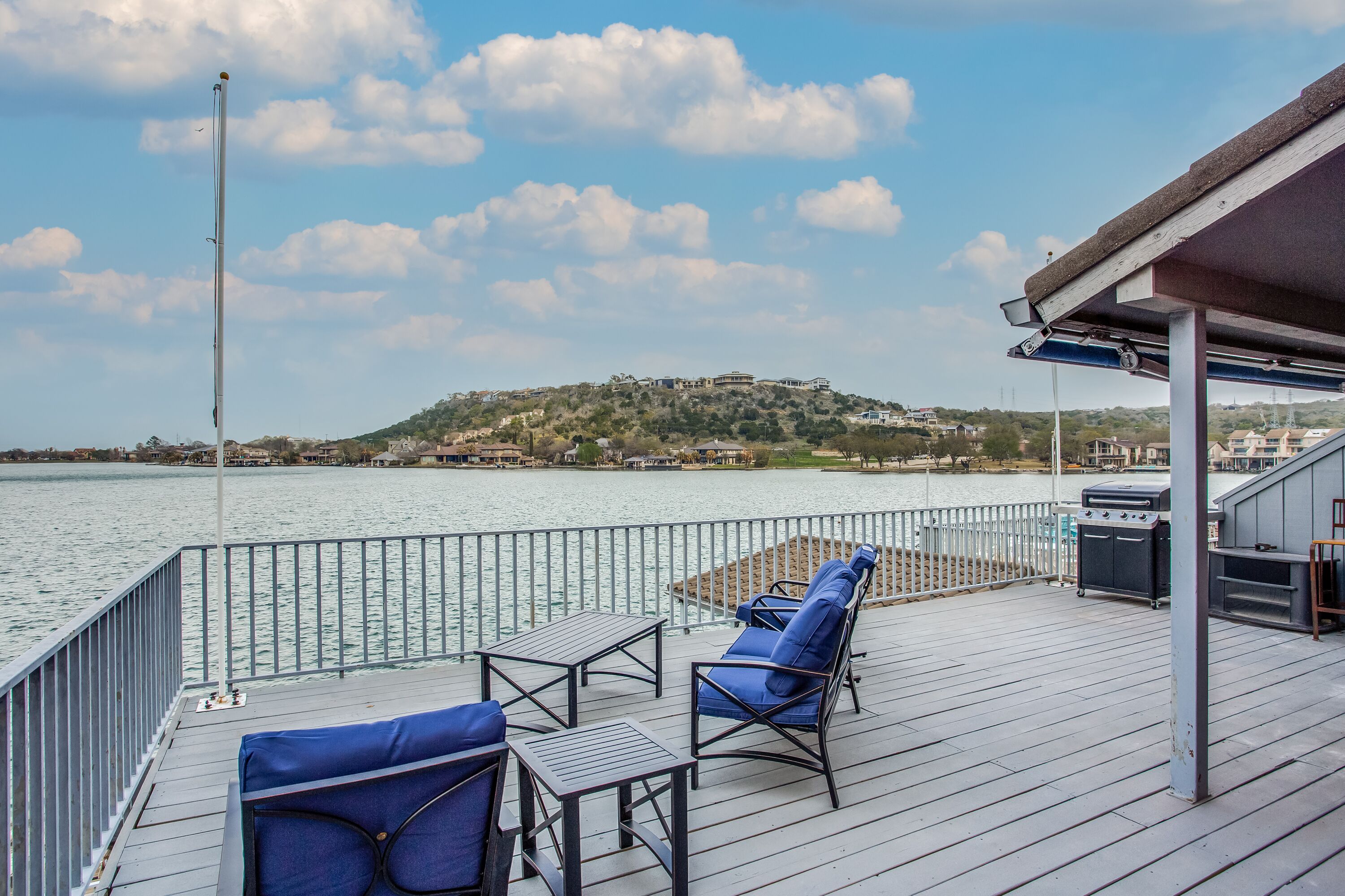 Eine Terrasse mit Sitzgelegenheit, Grill und Blick auf einen Hügel mit Gebäuden.