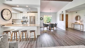 A modern kitchen with a central island, bar stools, and a dining area with a round table and chairs. - Palm Desert Escape w/ Patio, Grill & Fire Pit (Palm Desert)