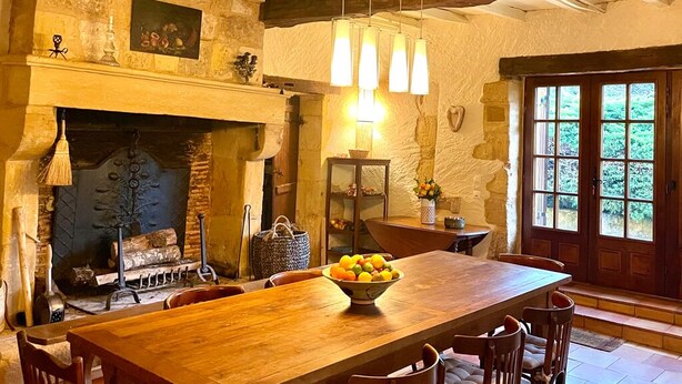 Un coin repas rustique avec une cheminée en pierre, une table en bois et des chaises.