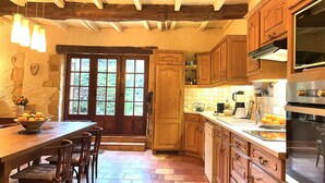 Une cuisine rustique avec des meubles de rangement en bois, une grande table à manger et un four encastré.