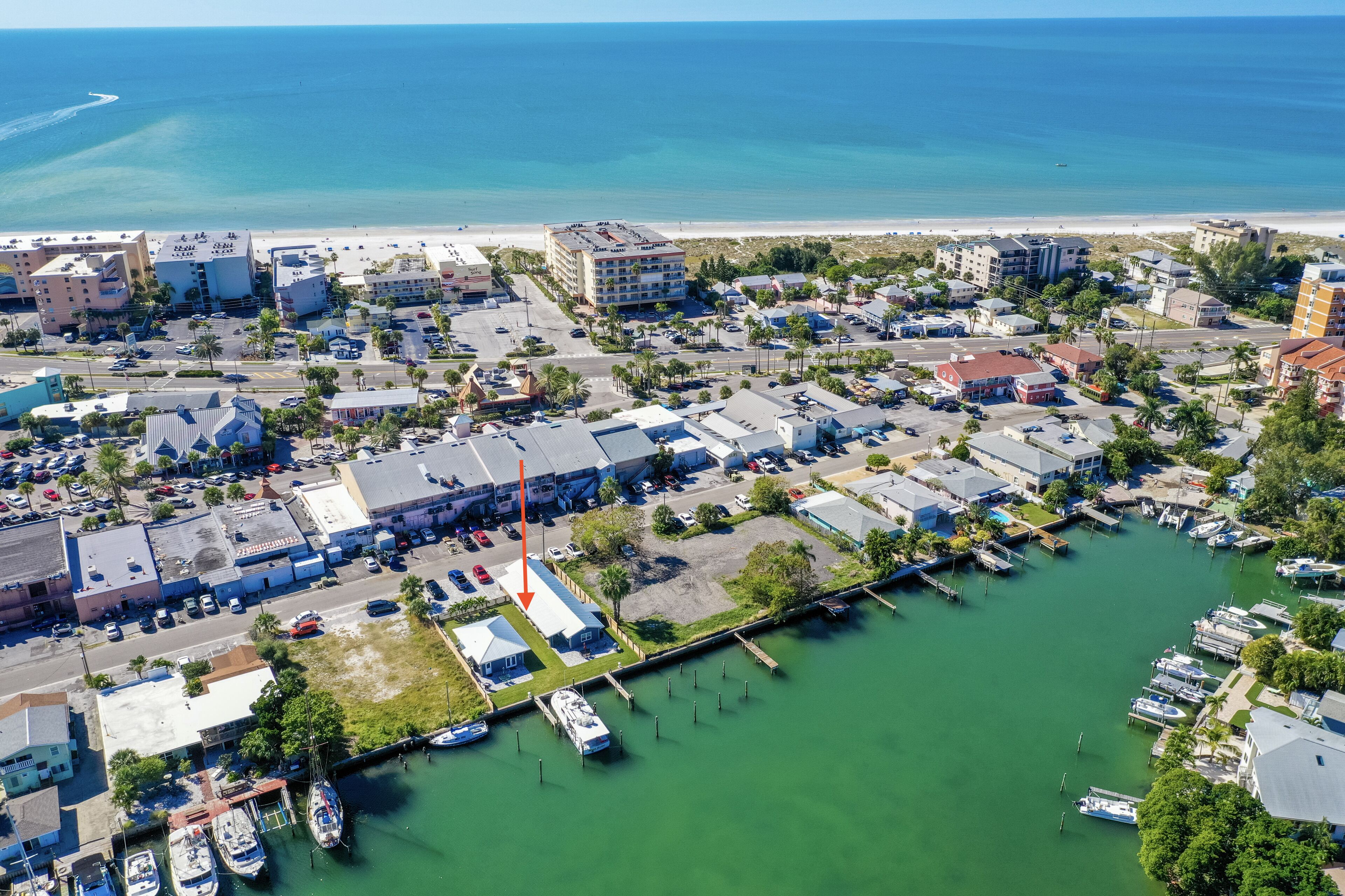An aerial view of a coastal town with a marina, buildings, and a beach.
