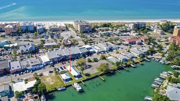 An aerial view of a coastal town with a marina, buildings, and a beach.