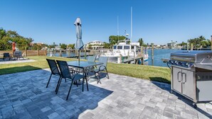 Eine Terrasse im Freien mit Grill, Stühlen und Blick auf den Hafen.