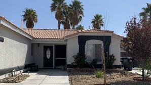 A residential house with a tiled roof, a front door, and a driveway leading to the entrance. - Coming soon (North Las Vegas)