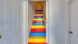 A staircase with alternating red, yellow, and blue steps leading to a door at the top.