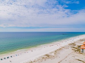 A beach with a pier extending into the ocean, white sand, and clear blue water. - Penthouse Views, Resort Amenities, and Luxe Furnishings! Book Today! (Pensacola Beach)