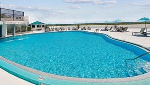 A swimming pool with lounge chairs and umbrellas, a building with a green roof, and a clear sky. - Edgewater #1205 | Gulf Front in Destin, Spectacular Views + Amenities (Miramar Beach)