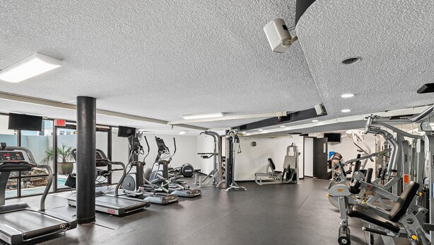 A gym with various exercise equipment, a large window, and a ceiling-mounted security camera. - Edgewater #1205 | Gulf Front in Destin, Spectacular Views + Amenities (Miramar Beach)
