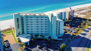 A high-rise hotel with multiple floors, a parking lot, and a beach view. - Perdido Sun #514 | Pool, Water Views, Beachfront! (Perdido Key)