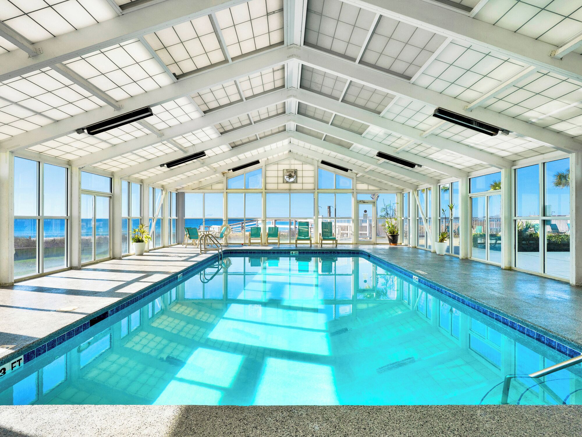 Una piscina interna con vista diretta sull'oceano attraverso ampie finestre.
