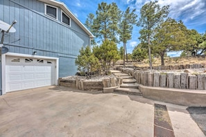 A residential property with a garage, a concrete driveway, and a landscaped area with trees and wooden planters.