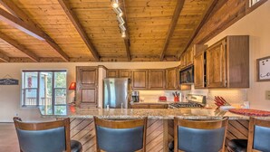 A kitchen with wooden cabinets, a stainless steel refrigerator, and a granite countertop. - Alto Cabin w/ Stunning Views, Hot Tub + Sauna! (Alto)