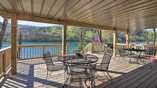 Um deck coberto com área de estar externa e vista para um lago.