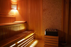 A sauna with wooden benches and a stone wall. - Safir Hotels Silivri (Silivri)