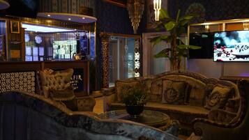 Un lobby lujoso con una zona de bar, un conjunto de sofás y una pantalla de televisión.