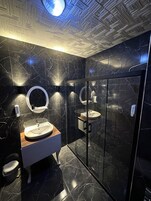 Habitación cuádruple Deluxe | Baño | Artículos de higiene personal de diseño, secador de pelo y zapatillas