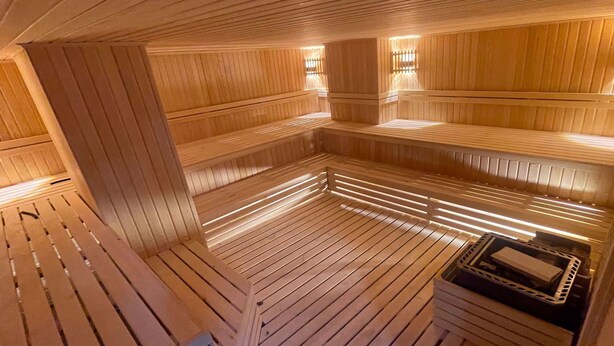 Eine Sauna mit Holzbänken und einer zentralen Heizung.