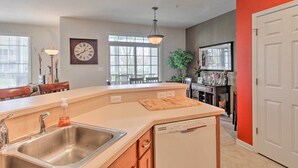 A kitchen with a dishwasher, a wooden island, a sink, and a dining area with chairs and a table. - 4 Mi to Bethany Beach: Sunny Escape w/ Porches! (Ocean View)