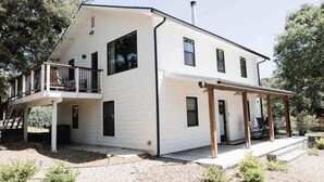 A two-story white house with a balcony and a covered porch. - The White Barn (Julian)