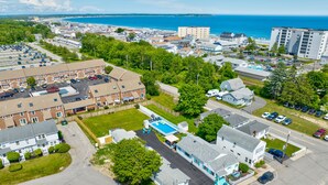 An aerial view of a residential area with a swimming pool, parking lots, and a beach in the background. - Seashell Cottages/JK Rentals - Cottage 1, 2 full beds, 1 twin (Old Orchard Beach)